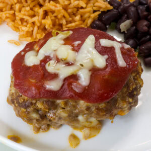 Close up of one serving of taco meatloaf on a plate with rice and beans..