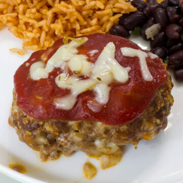 Close up of one serving of taco meatloaf on a plate with rice and beans..