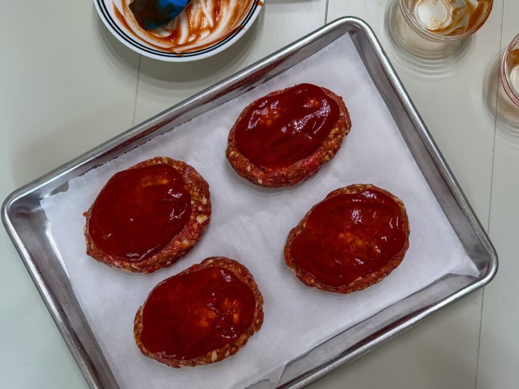 The portioned out taco meatloaf topped with a ketchup and taco sauce mixture and ready to go into the oven.