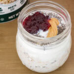 One jar with quick oats, milk, chia seeds, peanut butter and jelly in it before being mixed together and refrigerated.