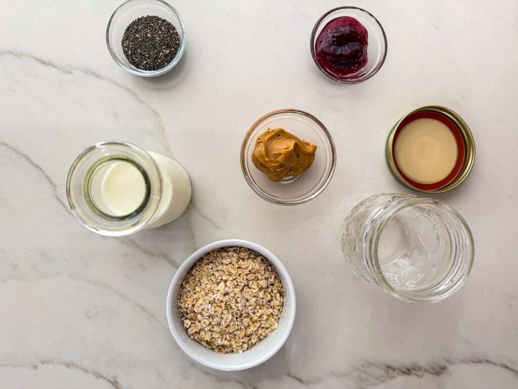 The milk, chia seeds, jelly, peanut butter, oats, and mason jar needed to make PB&J Overnight Oats.