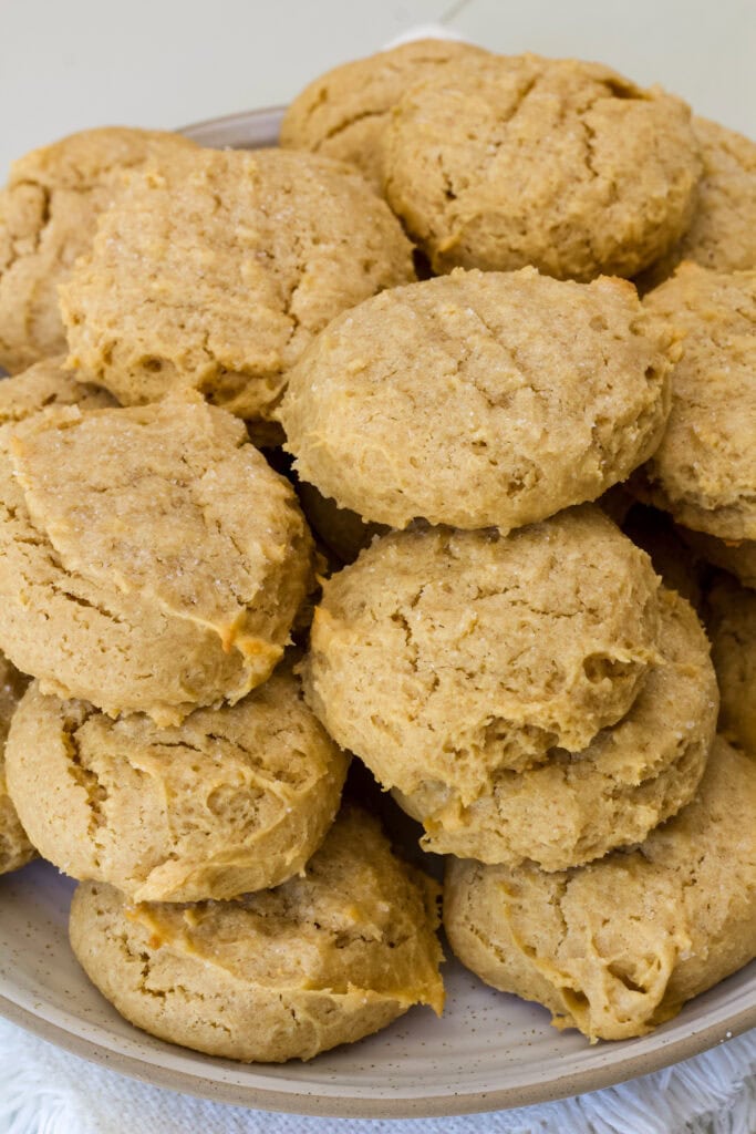 Many peanut butter cake mix cookies on stacked on a plate.