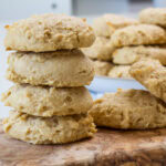 Close up of four cookies stacked and many cookies in the background.