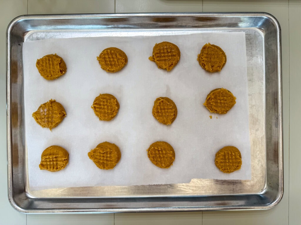 The cookie dough portioned out and flattened slightly with a fork ready to go into the oven.