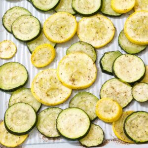 A closeup of roasted zucchini and summer squash on a sheet pan after it's been cooked.
