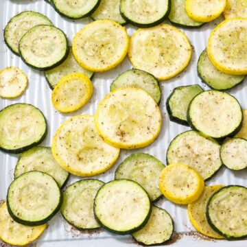 A closeup of roasted zucchini and summer squash on a sheet pan after it's been cooked.