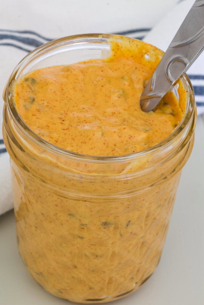 A small mason jar full of Big Mac sauce with a spoon sticking out of it.