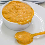 A small white bowl on a plate full of Big Mac sauce and a spoonful sitting in front of it.