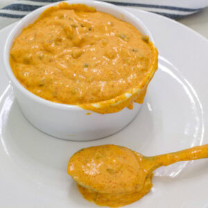 A small white bowl on a plate full of Big Mac sauce and a spoonful sitting in front of it.
