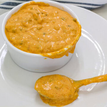 A small white bowl on a plate full of Big Mac sauce and a spoonful sitting in front of it.