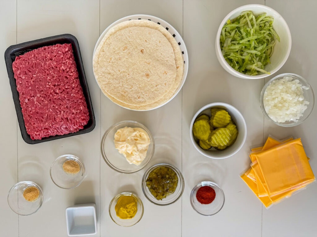Ground beef, flour tortillas, shredded lettuce, cheese slices, pickles, onions, and seasonings for Big Mac smash tacos and homemade big mac sauce.