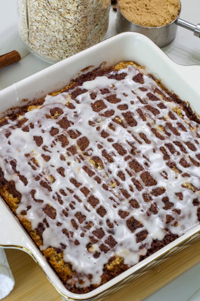 The whole casserole dish with uncut cinnamon roll baked oatmeal drizzled with icing.