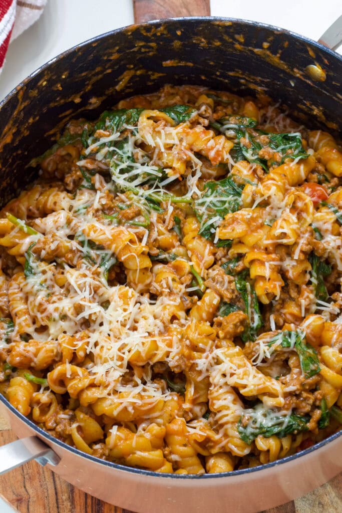 Closeup overhead of a pan filled with One Pot Ground Beef Pasta topped with parmesan cheese.