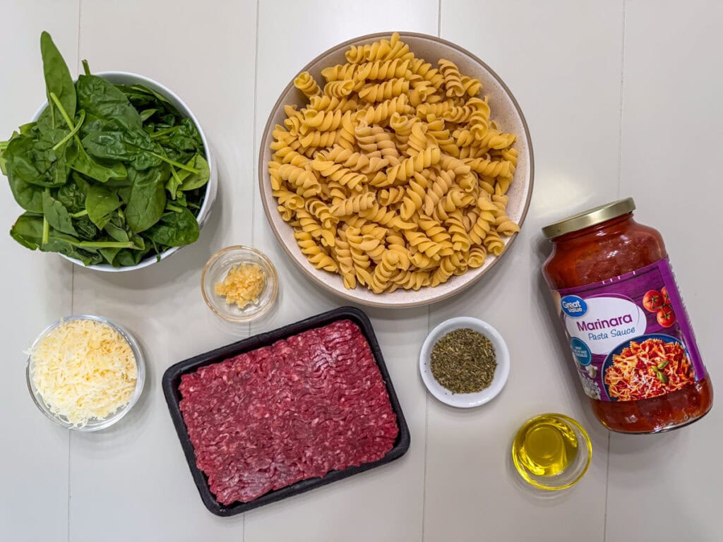The spinach, pasta, cheese, garlic, ground beef, Italian seasoning and olive oil measured out to make One Pot Ground Beef Pasta.