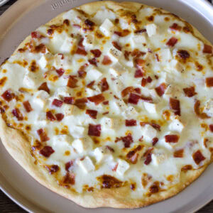 Closeup overhead of a whole uncut chicken bacon ranch pizza.