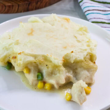 Closeup side view of one serving of chicken shepherd's pie on a white plate.