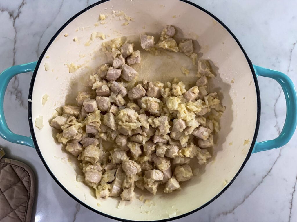 Flour added to the browned chicken in a large pan.