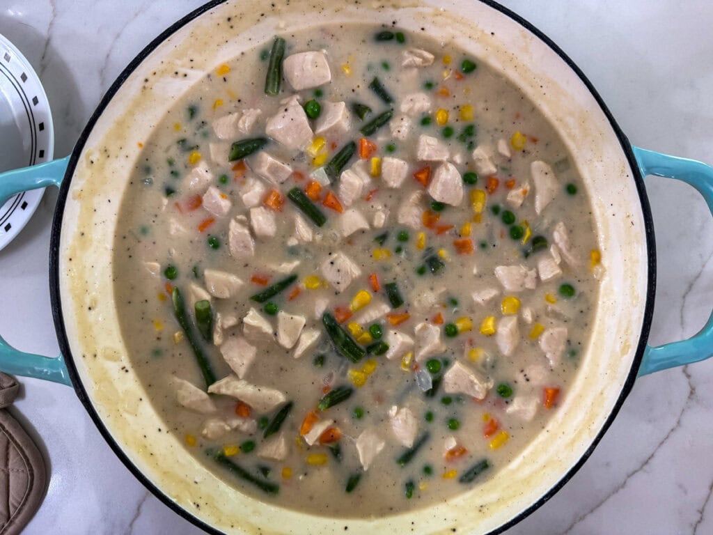 The frozen mixed vegetables added to the chicken and gravy in the pan.