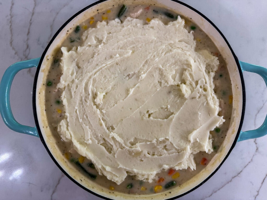 A layer of mashed potatoes on top of the chicken, vegetable and gravy mixture.