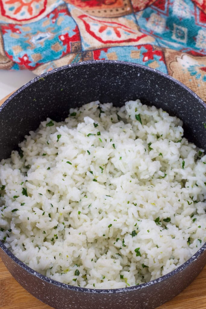 A small black and white saucepan with cooked cilantro lime rice in it.