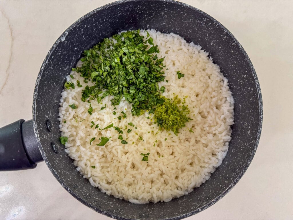 Fresh cilantro, lime juice and lime zest added to the small saucepan on top of the cooked white rice.
