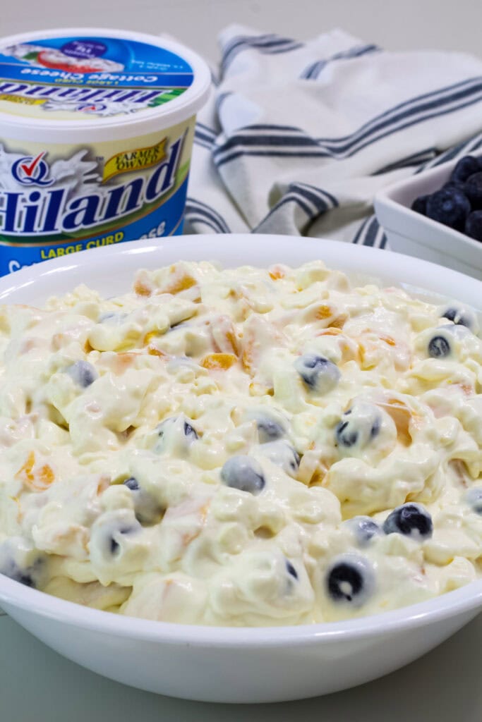 Closeup side shot of Cottage Cheese Fruit Salad with Peaches and Blueberries in a white serving bowl.
