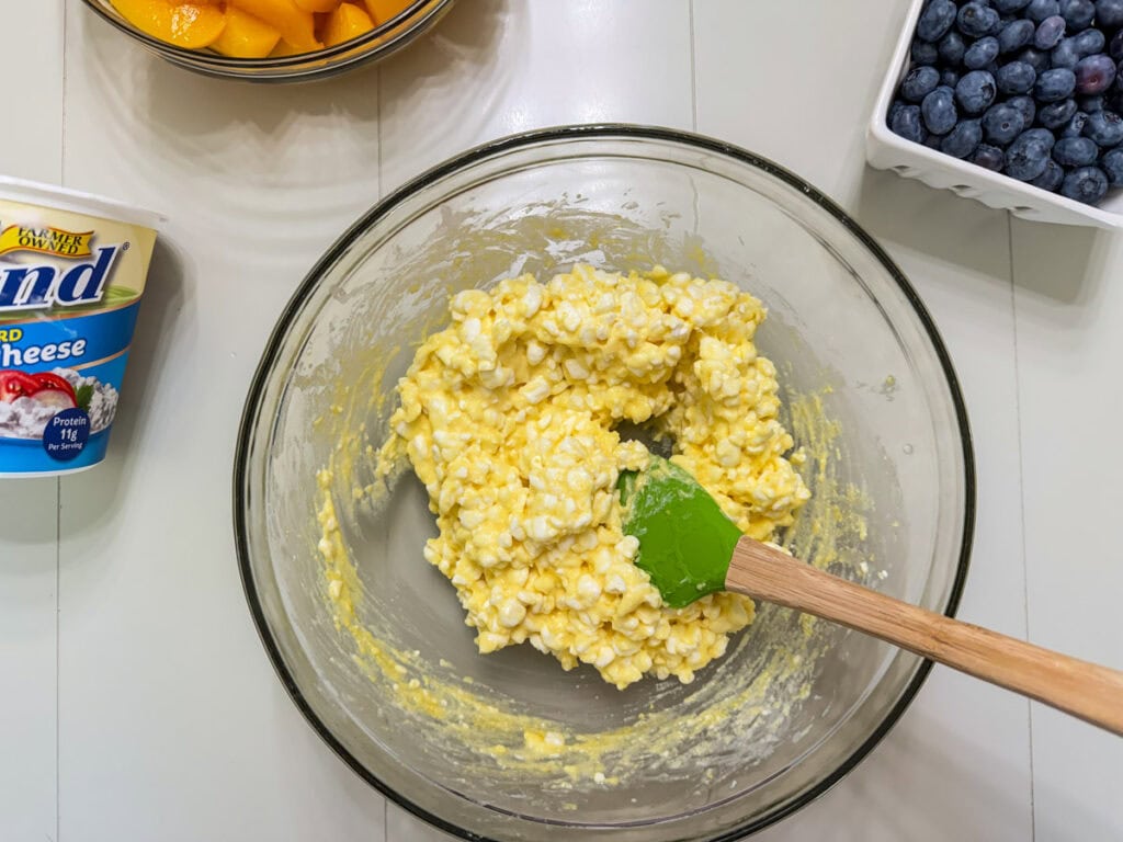 The cottage cheese and dry instant pudding mix combined in a glass mixing bowl.