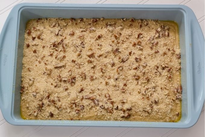 The cake batter in the cake pan topped with nut crumb topping.