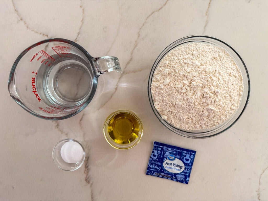The water, flour, olive oil, salt and yeast measured out to make the no-knead pizza dough.