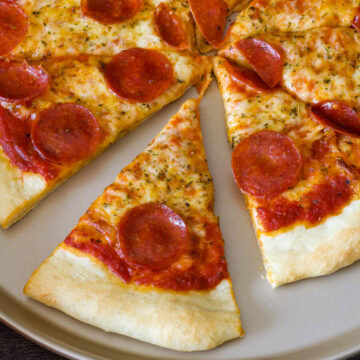 Closeup of part of a pepperoni pizza with one slice pulled out.