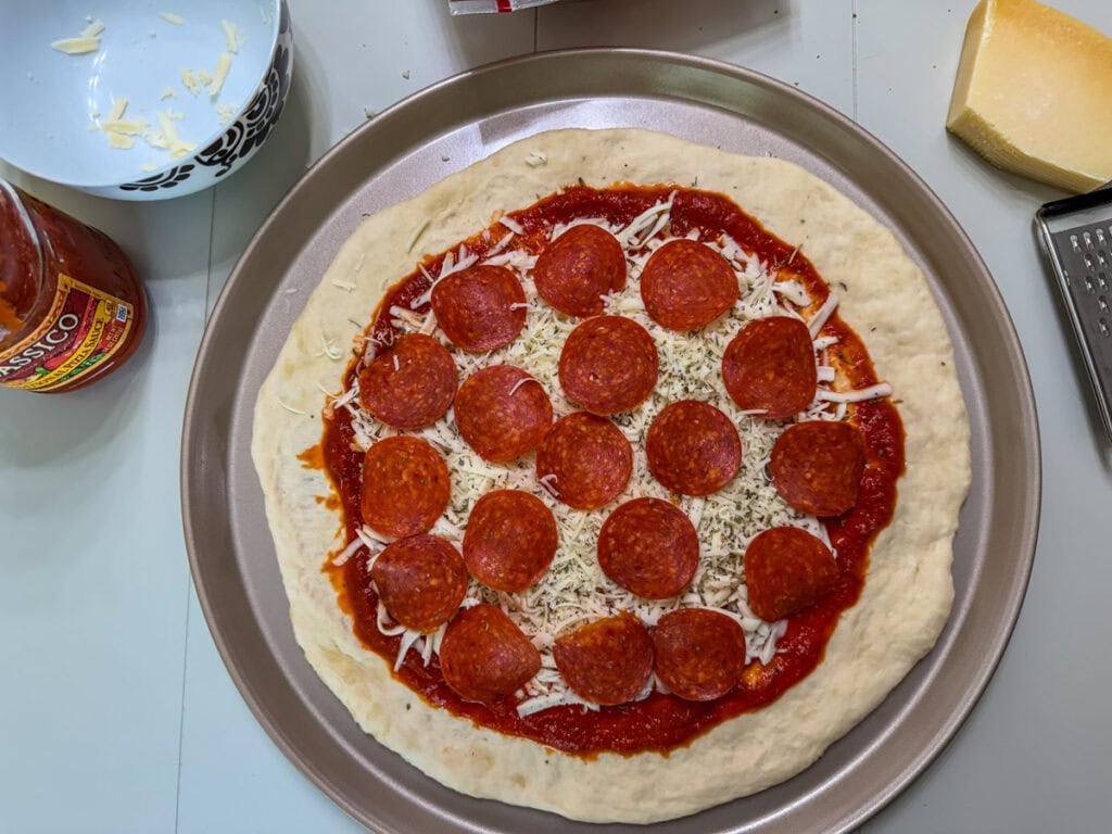 Pepperoni slices on top of the pizza sauce and cheese.