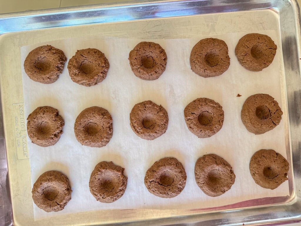 A sheet pan of baked cookies with the indent before putting the coconut on top.