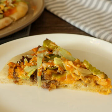 One slice of big mac pizza on a white plate.
