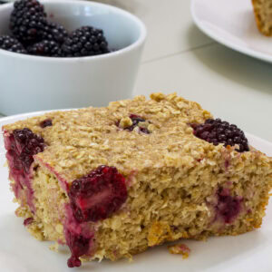 Closeup side view of one serving of blackberry baked oatmeal on a white plate.