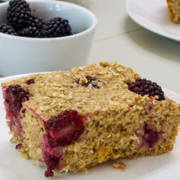 Closeup side view of one serving of blackberry baked oatmeal on a white plate.