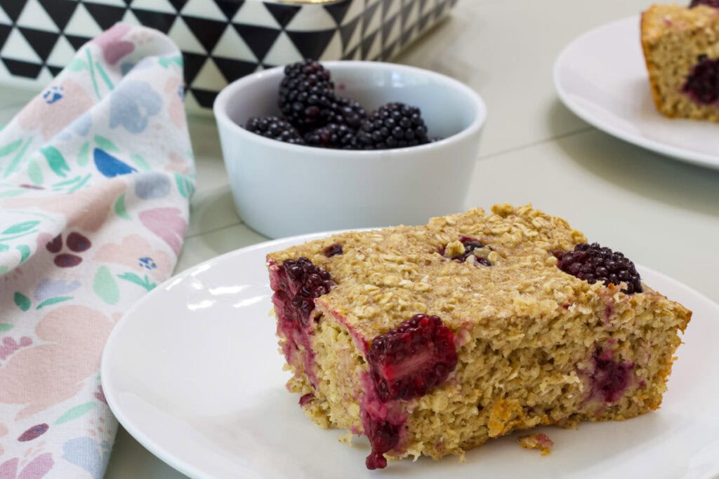 One serving of blackberry baked oatmeal in the foreground and a small bowl of blackberries in the background.