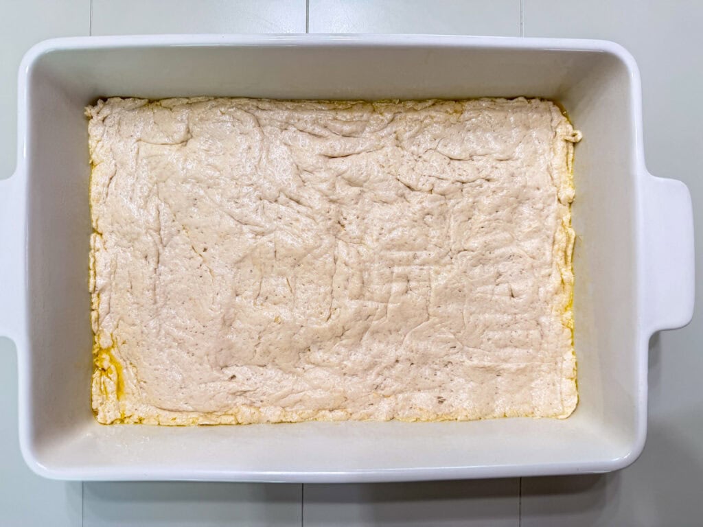 The biscuit layer pressed into the casserole dish.