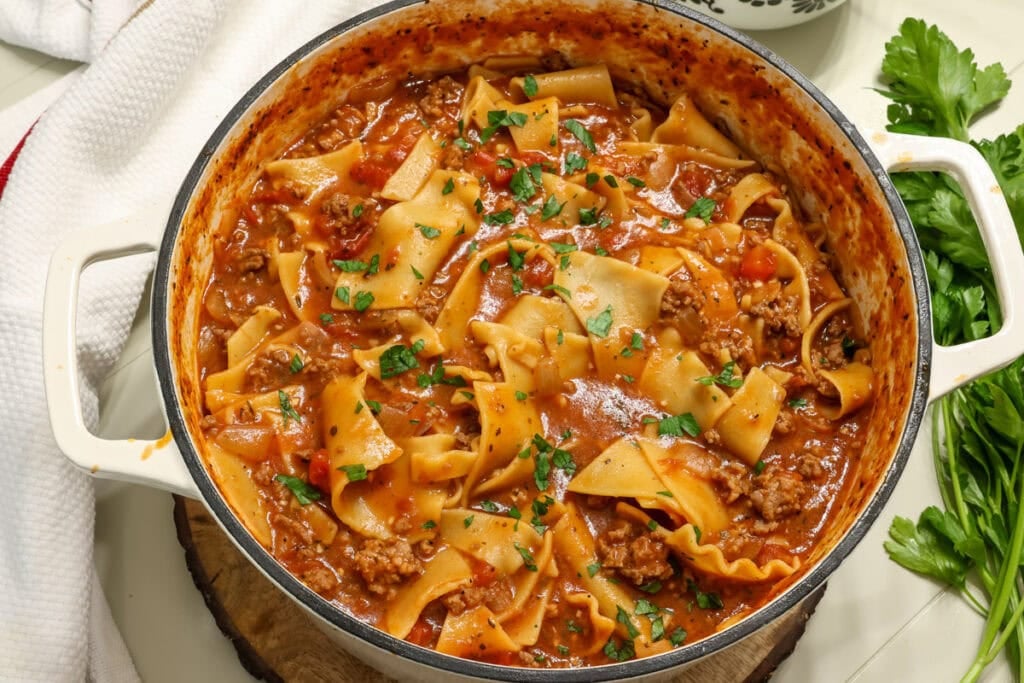 Closeup overhead of a large pot of hearty lasagna soup topped with chopped fresh parsley.