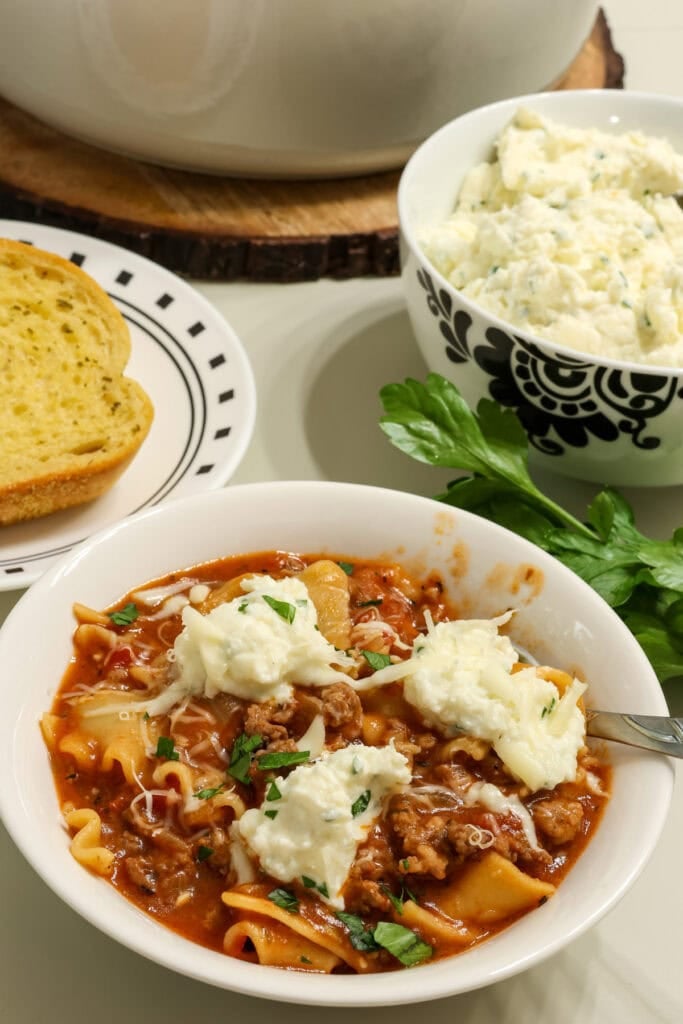 A bowl of lasagna soup topped with three dollops of a ricotta and mozzarella cheese mixture.