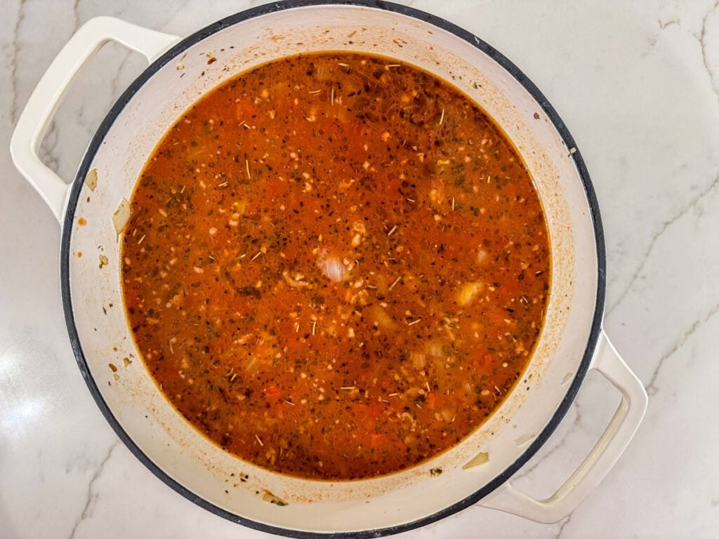 The ground beef, sausage, onion, marinara sauce and beef broth in a large pot.