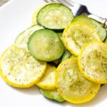 Closeup of one serving of roasted zucchini and summer squash on a white plate.
