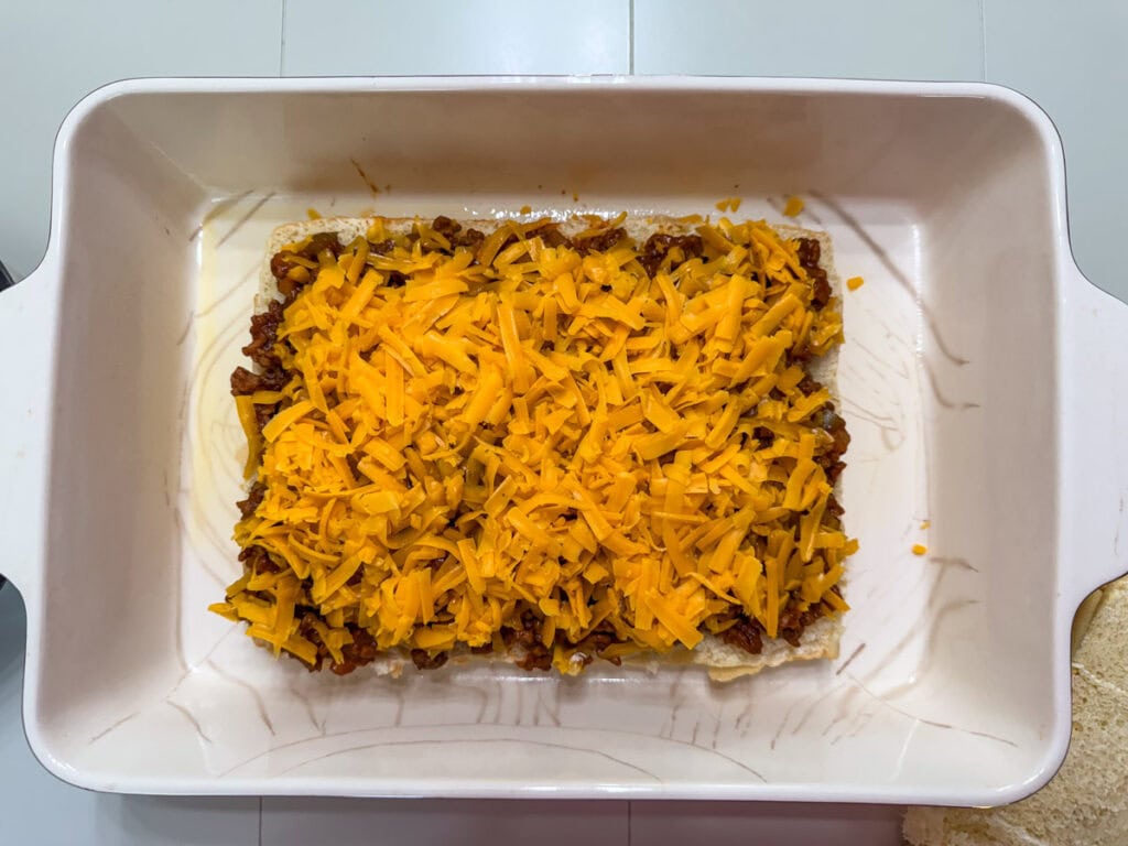 Grated cheddar cheese spread over the sloppy joe mixture.