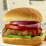 Very closeup side vie of an air fryer turkey burger on a bun with toppings.