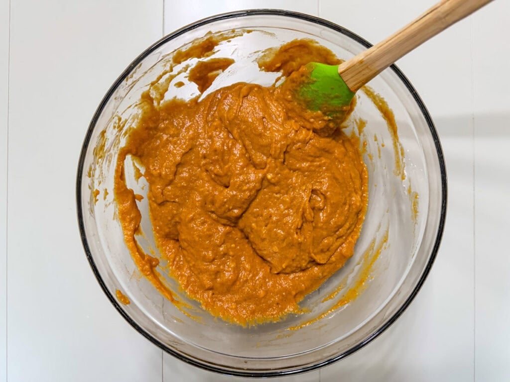 The wet and dry ingredients combined in a large glass mixing bowl.