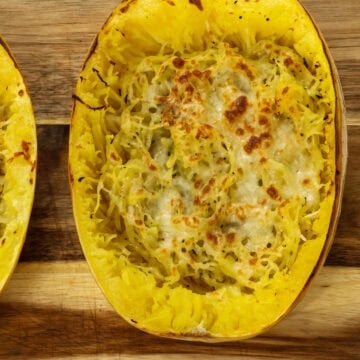 Very closeup overhead shot of one half of a baked spaghetti squash on a wooden cutting board.