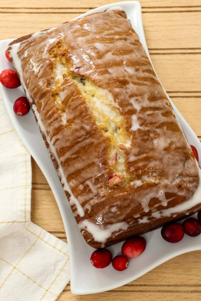 Closeup overhead of a whole uncut loaf of cranberry bread topped with vanilla glaze.