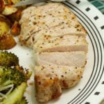 Side closeup of a sliced air fried pork chop on a plate with side dishes.