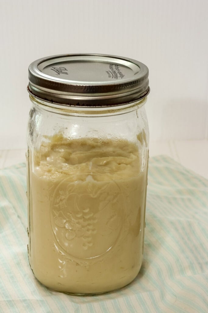 Closeup side view of a large mason jar filled about three-fourths of the way with homemade cream of chicken soup.