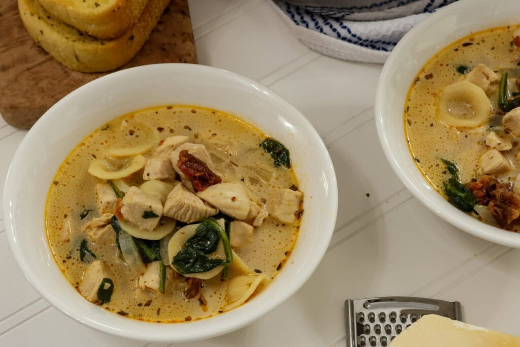 Closeup side view of a bowl of Marry Me Chicken Soup with a partially visible bowl next to it.