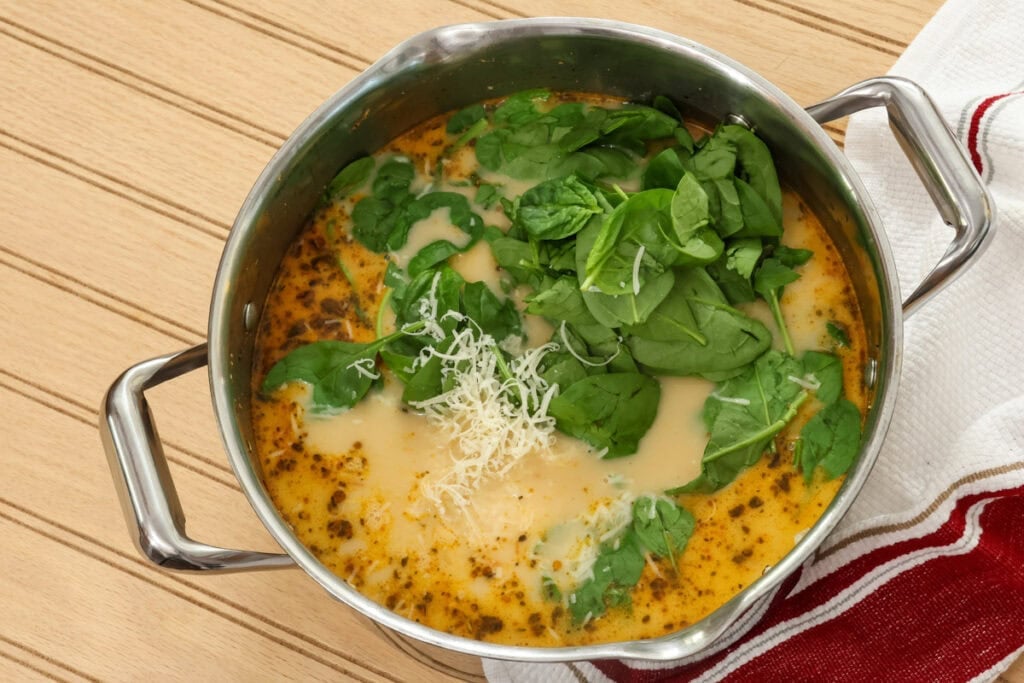 Chicken broth, heavy cream, spinach and parmesan cheese added to the pot with the chicken and sun dried tomatoes.